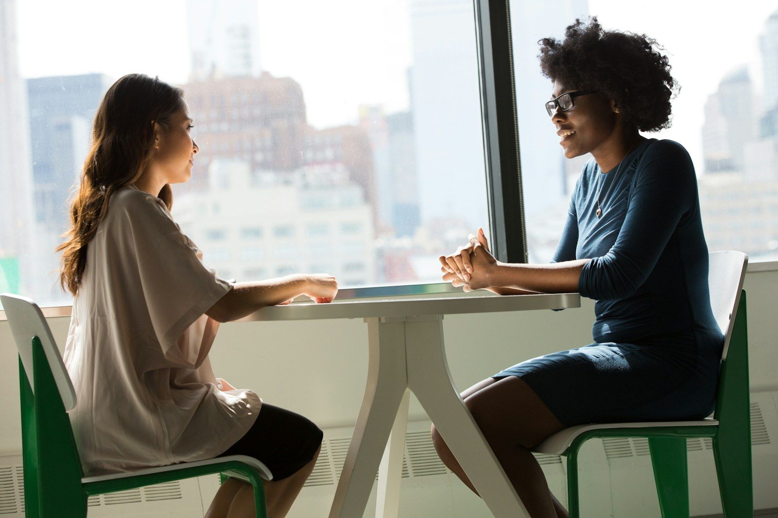 Deux jeunes femmes échangent face à face autour d'une table