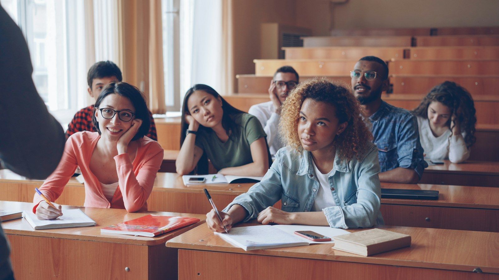 Jeunes adultes attentifs, prenant des notes dans une salle de cours